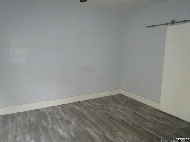 unfurnished room featuring dark hardwood / wood-style floors and a barn door