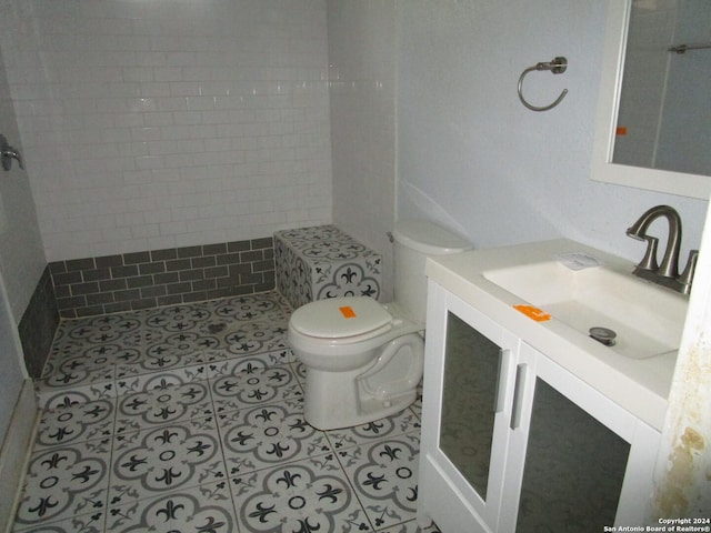 bathroom with tiled shower, vanity, toilet, and tile patterned flooring