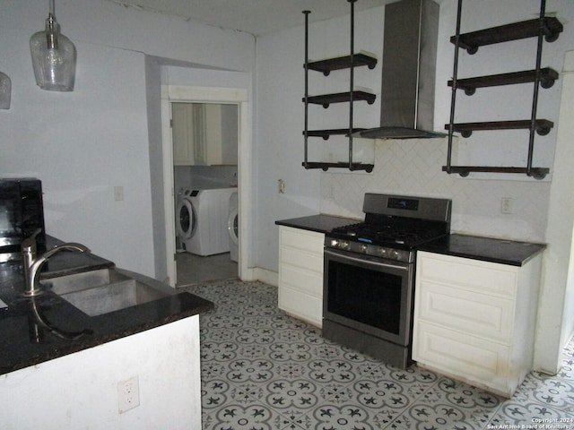 kitchen featuring backsplash, sink, washing machine and dryer, stainless steel range oven, and white cabinetry