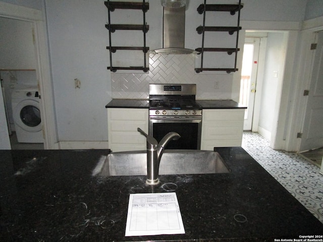 kitchen with white cabinetry, wall chimney range hood, tasteful backsplash, washer / dryer, and stainless steel stove