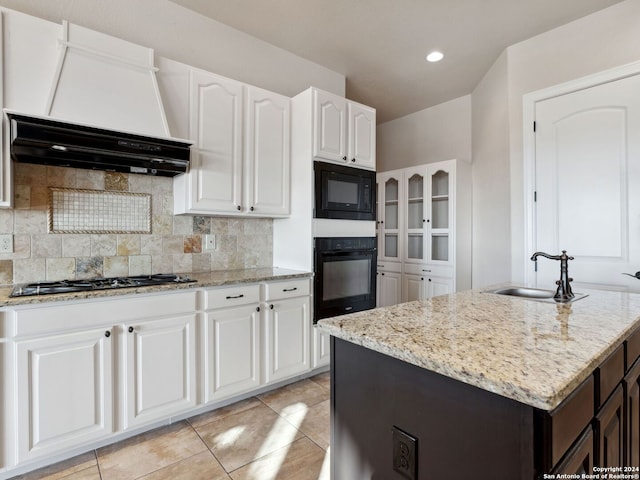 kitchen featuring a kitchen island with sink, white cabinetry, sink, and black appliances