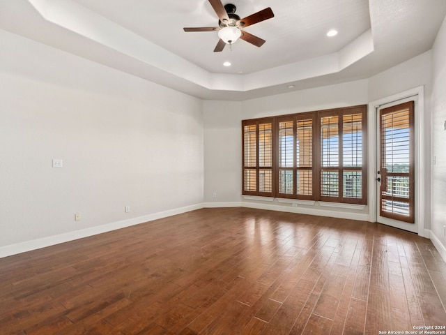 unfurnished room with a tray ceiling, ceiling fan, and dark hardwood / wood-style floors