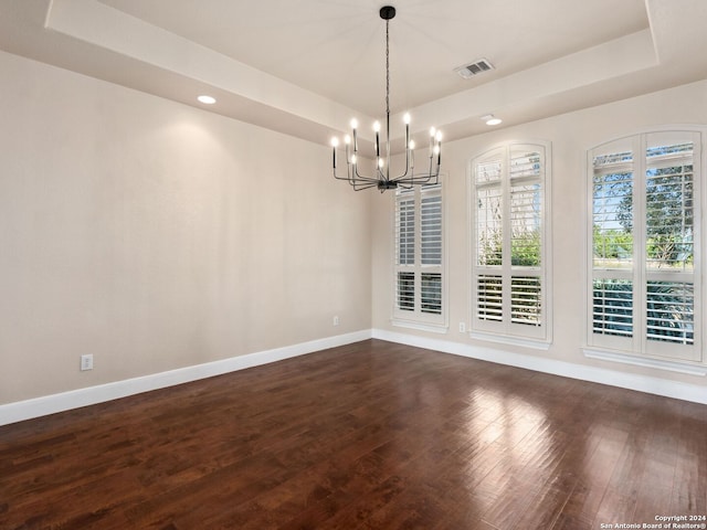 unfurnished dining area with a tray ceiling, dark hardwood / wood-style flooring, and a chandelier