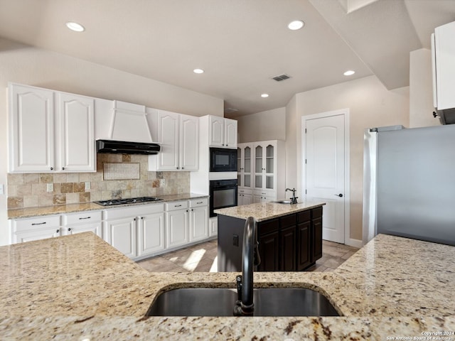 kitchen with light stone countertops, white cabinets, and black appliances