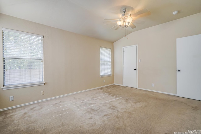 empty room with ceiling fan, light colored carpet, and vaulted ceiling