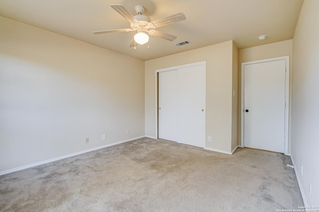 unfurnished bedroom featuring a closet, light colored carpet, and ceiling fan