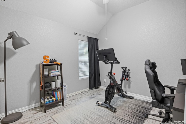 workout area with light hardwood / wood-style floors and lofted ceiling