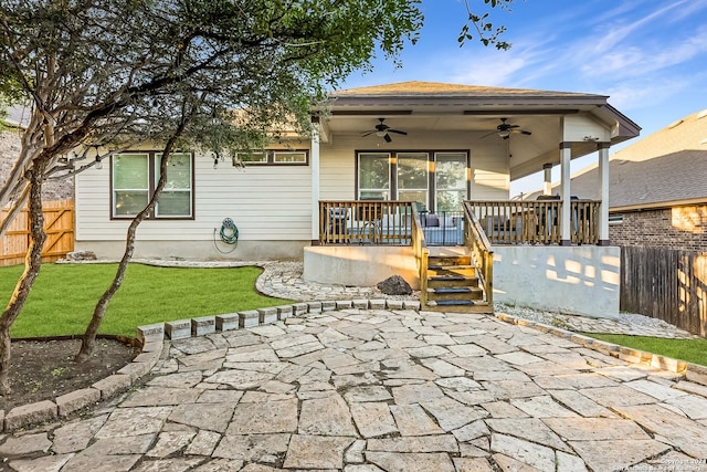 back of house with ceiling fan and a lawn