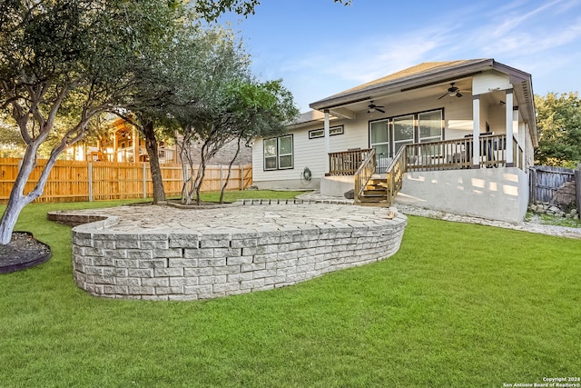 rear view of property with ceiling fan, a wooden deck, and a lawn