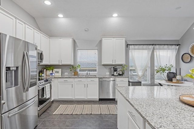 kitchen featuring a healthy amount of sunlight, white cabinetry, appliances with stainless steel finishes, and vaulted ceiling