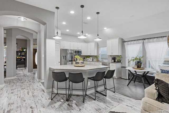 kitchen featuring pendant lighting, a center island, white cabinets, light hardwood / wood-style flooring, and stainless steel appliances