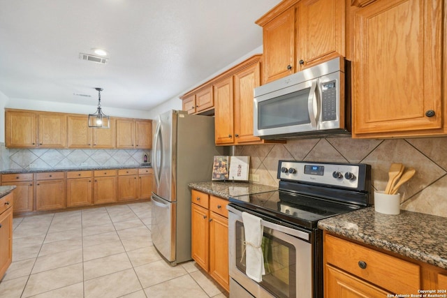 kitchen with pendant lighting, decorative backsplash, dark stone countertops, light tile patterned floors, and stainless steel appliances