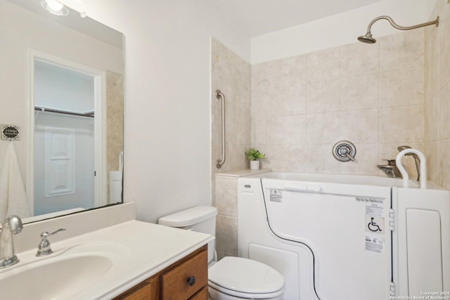 bathroom featuring a tile shower, vanity, and toilet