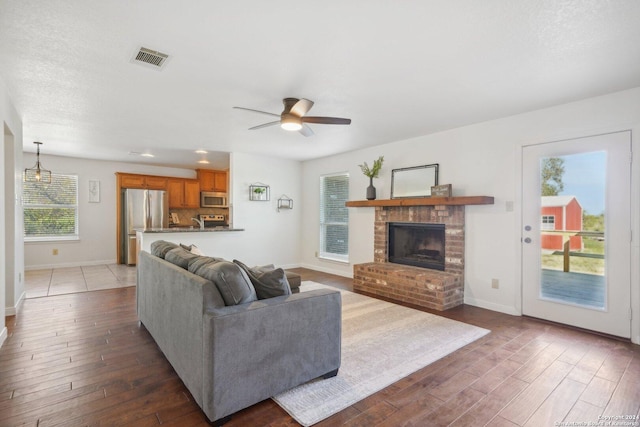 living room featuring ceiling fan, a fireplace, and dark wood-type flooring