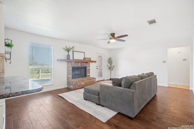 living room with ceiling fan, a fireplace, and dark hardwood / wood-style floors