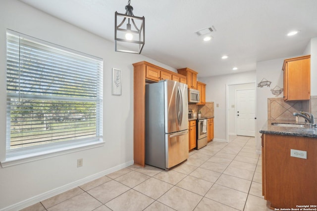 kitchen featuring backsplash, sink, appliances with stainless steel finishes, decorative light fixtures, and light tile patterned flooring