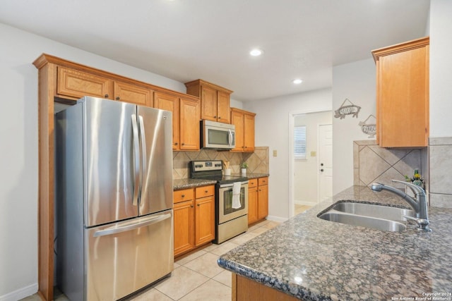 kitchen with dark stone counters, sink, decorative backsplash, light tile patterned floors, and stainless steel appliances