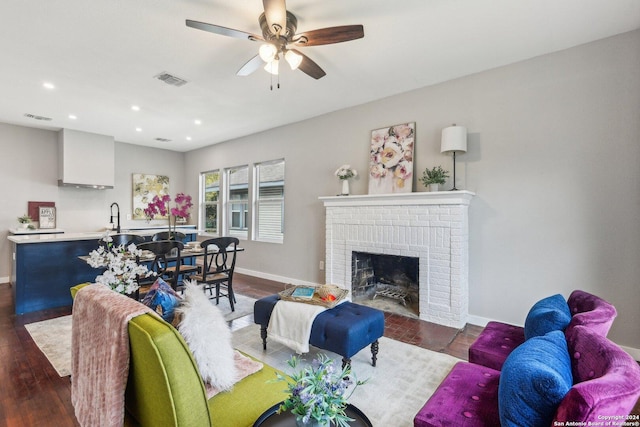 living room with ceiling fan, a fireplace, dark wood-type flooring, and sink