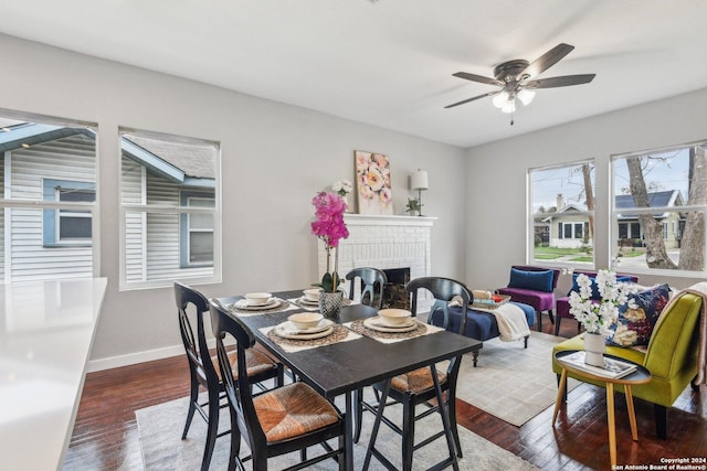 dining area featuring a fireplace, dark hardwood / wood-style floors, and ceiling fan