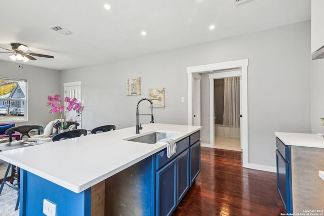 kitchen featuring blue cabinetry, dark hardwood / wood-style flooring, sink, and a kitchen island with sink