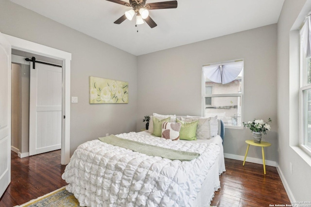 bedroom with ceiling fan, a barn door, dark wood-type flooring, and multiple windows