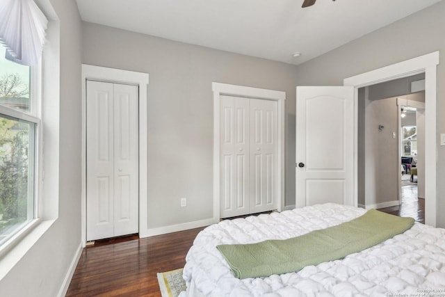 bedroom with two closets, ceiling fan, and dark wood-type flooring