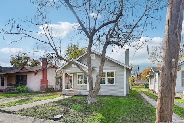 bungalow-style home featuring covered porch and a front lawn