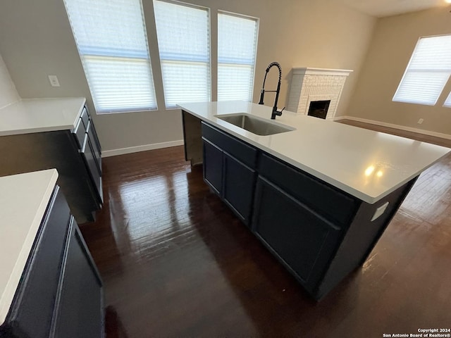 kitchen featuring dark hardwood / wood-style flooring, a kitchen island with sink, sink, and plenty of natural light