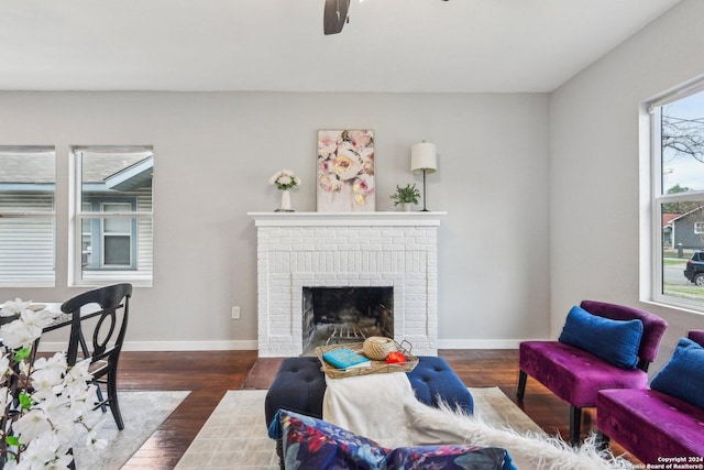 living room with a fireplace, dark hardwood / wood-style flooring, and ceiling fan