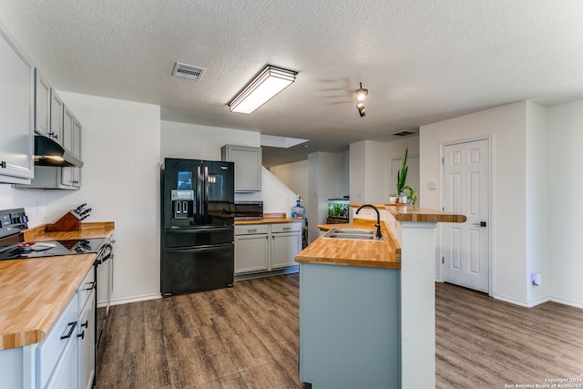 kitchen featuring wooden counters, black refrigerator with ice dispenser, stainless steel range with electric stovetop, and sink