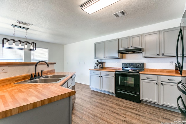 kitchen with butcher block countertops, black electric range oven, and hardwood / wood-style floors