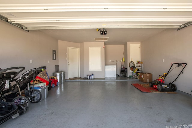 garage featuring electric panel, white fridge, and a garage door opener