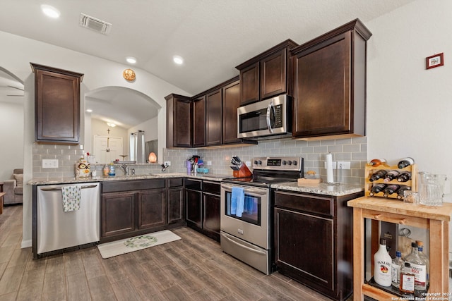 kitchen with tasteful backsplash, dark hardwood / wood-style flooring, lofted ceiling, and appliances with stainless steel finishes