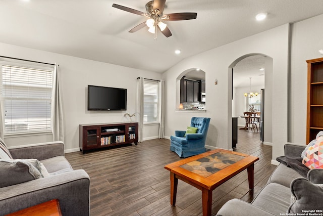 living room featuring ceiling fan with notable chandelier, dark hardwood / wood-style floors, and vaulted ceiling