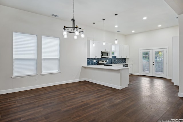 kitchen with kitchen peninsula, dark hardwood / wood-style flooring, stainless steel appliances, white cabinets, and hanging light fixtures