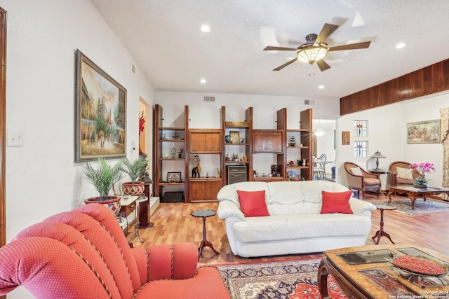 living room featuring ceiling fan, light wood-type flooring, and a textured ceiling