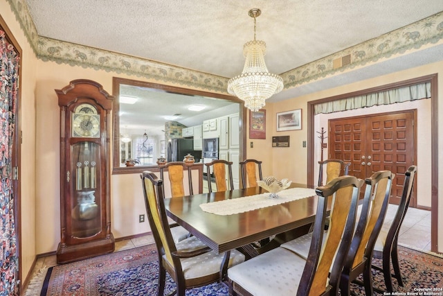 dining area with light tile patterned floors, a textured ceiling, and an inviting chandelier