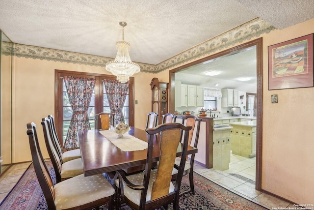 tiled dining area featuring sink, a textured ceiling, and a chandelier