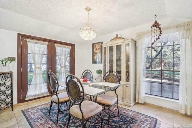 dining space featuring french doors, light tile patterned floors, a chandelier, and a textured ceiling