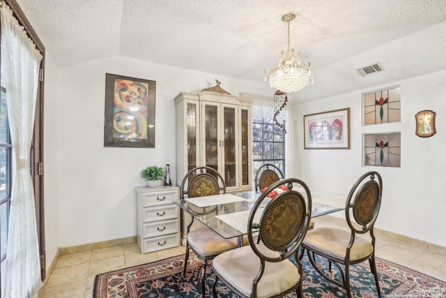 tiled dining space with a notable chandelier, a textured ceiling, and vaulted ceiling