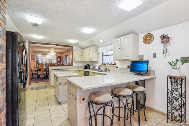 kitchen with sink, kitchen peninsula, a textured ceiling, a breakfast bar area, and black appliances