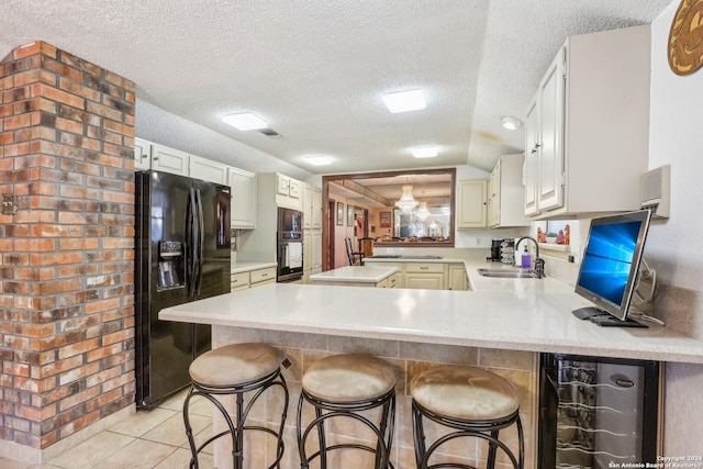 kitchen with kitchen peninsula, a kitchen breakfast bar, a textured ceiling, sink, and black appliances