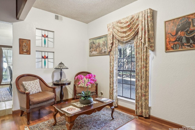 sitting room with a wealth of natural light, a textured ceiling, and hardwood / wood-style flooring