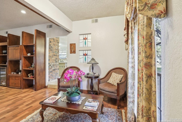 living area with hardwood / wood-style floors, plenty of natural light, a textured ceiling, and wine cooler