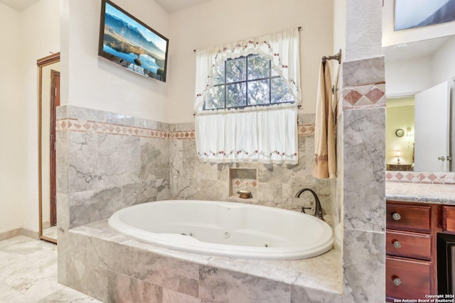 bathroom featuring vanity and tiled tub