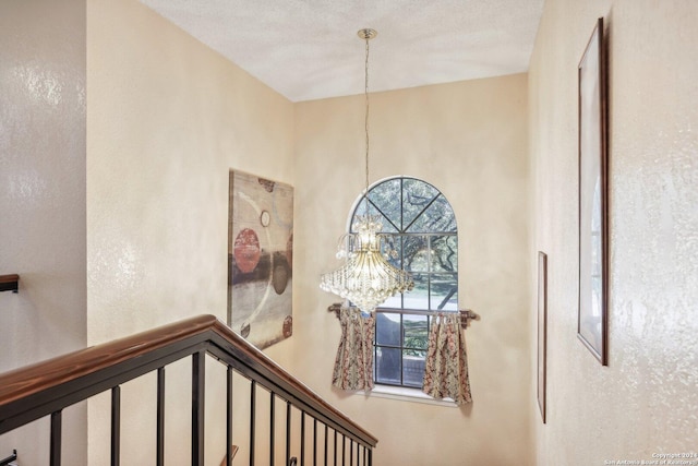 staircase with a chandelier and a textured ceiling