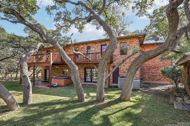 rear view of house featuring french doors, a hot tub, central air condition unit, a wooden deck, and a patio area