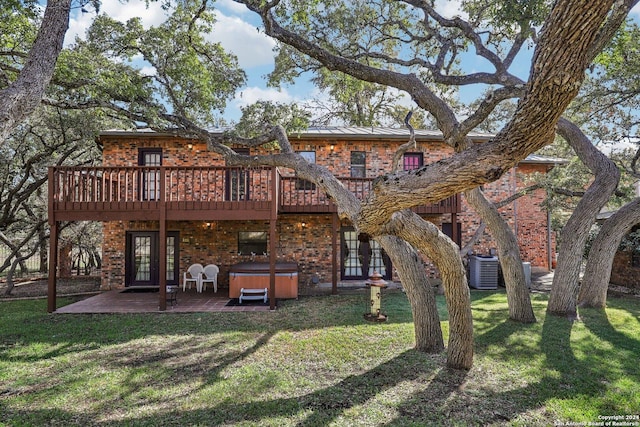 back of house featuring a lawn, central AC, a patio area, a deck, and a hot tub