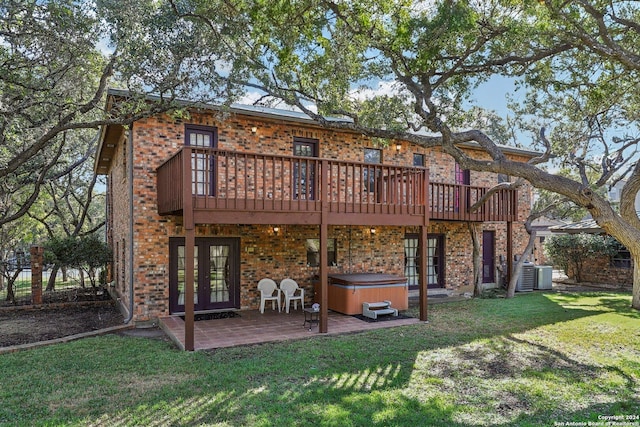 rear view of property with a wooden deck, central AC, a patio, a hot tub, and a lawn