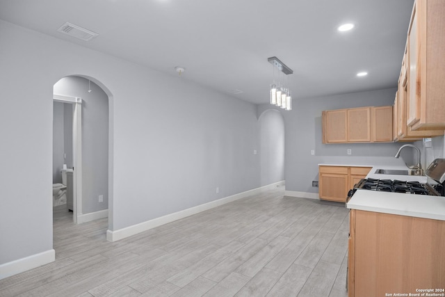 kitchen with light brown cabinets, light hardwood / wood-style flooring, pendant lighting, and sink